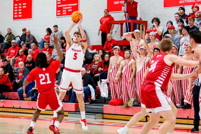 a basketball player in a red uniform jumping to shoot a basketball