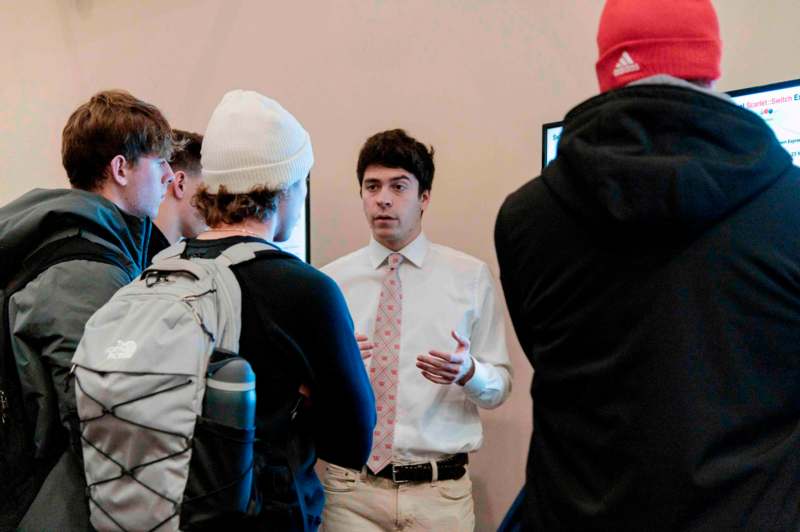 a man in a white shirt and tie talking to a group of people