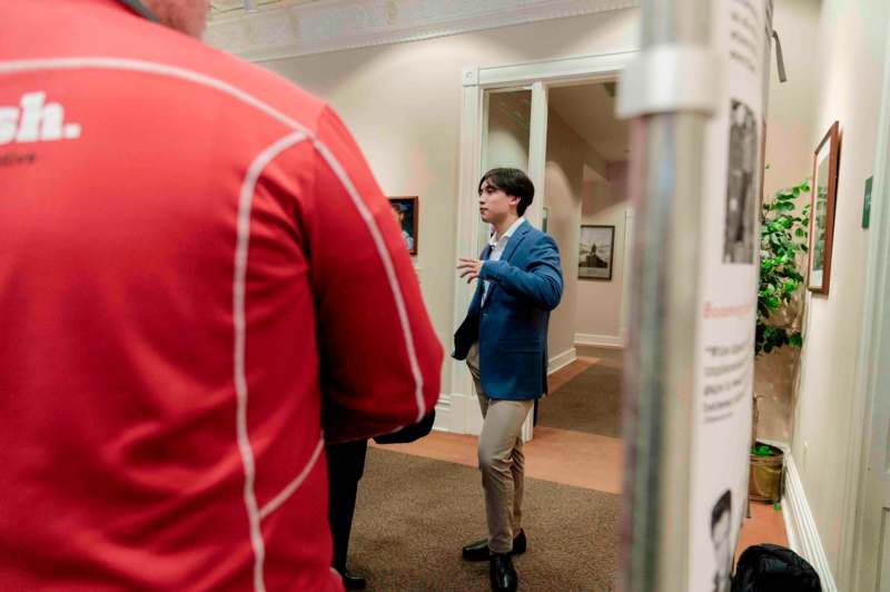 a man in a blue jacket talking to a man in a red jacket