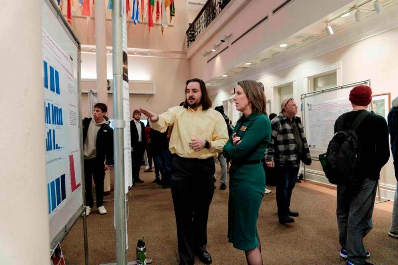 a man and woman standing in a room with a white board