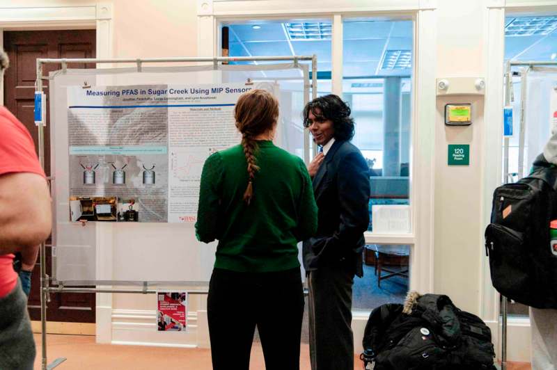 a woman standing next to a woman looking at a poster