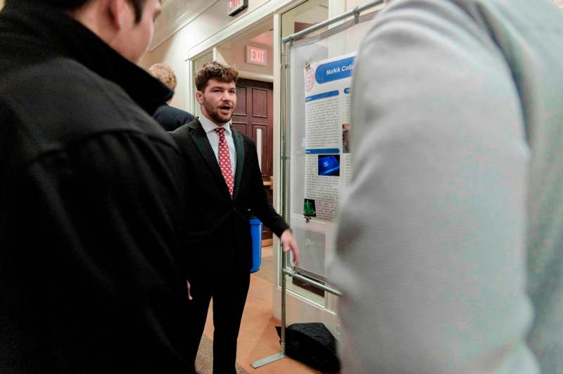 a man in a suit and tie standing in front of a poster