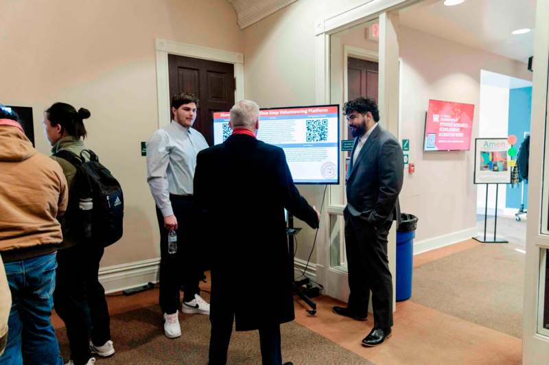 a group of men standing in a room looking at a screen