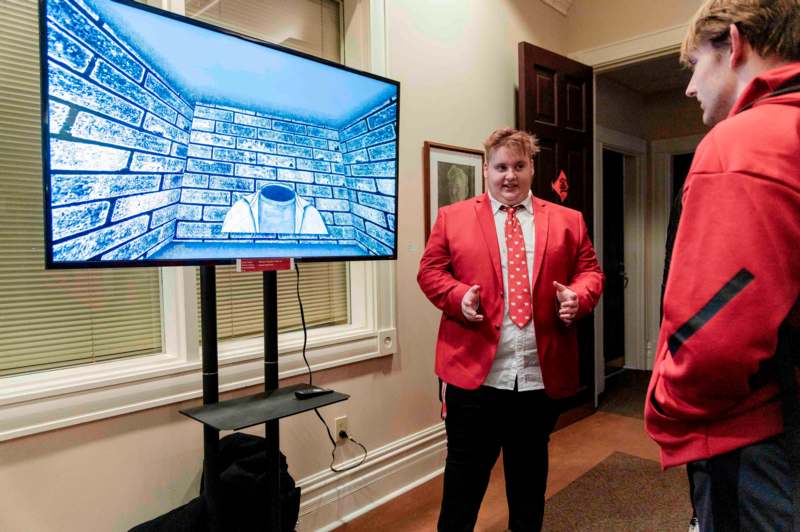 a man in a red suit and tie standing in front of a television