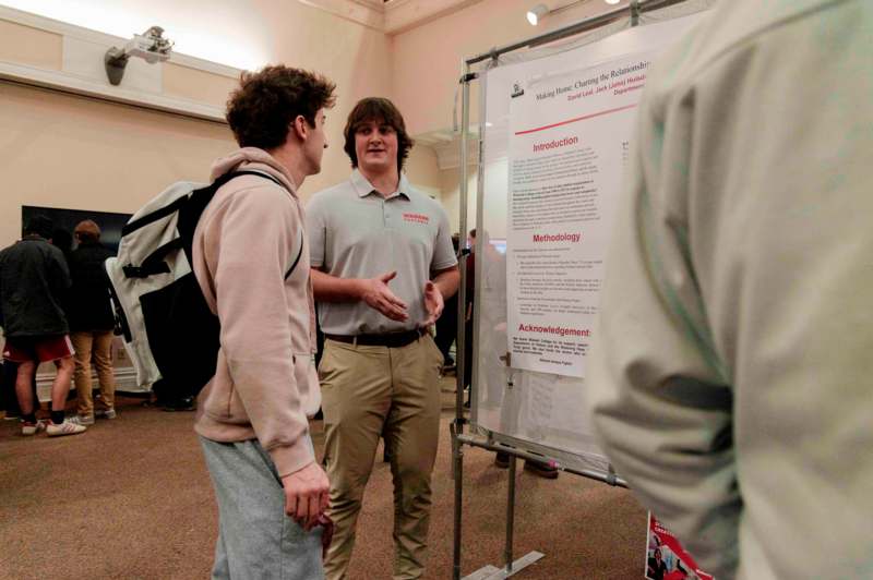 a man standing next to a man standing next to a poster