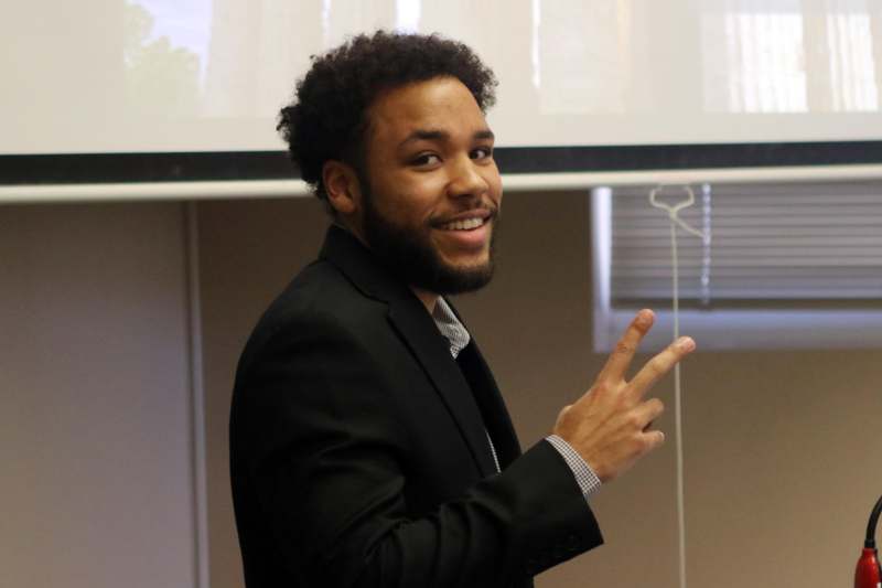 a man in a suit holding up two fingers