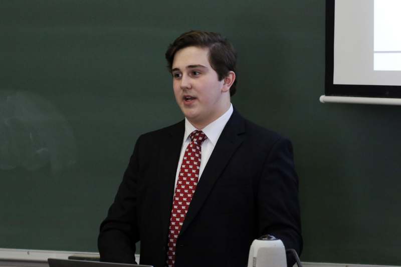 a man in a suit and tie standing in front of a chalkboard