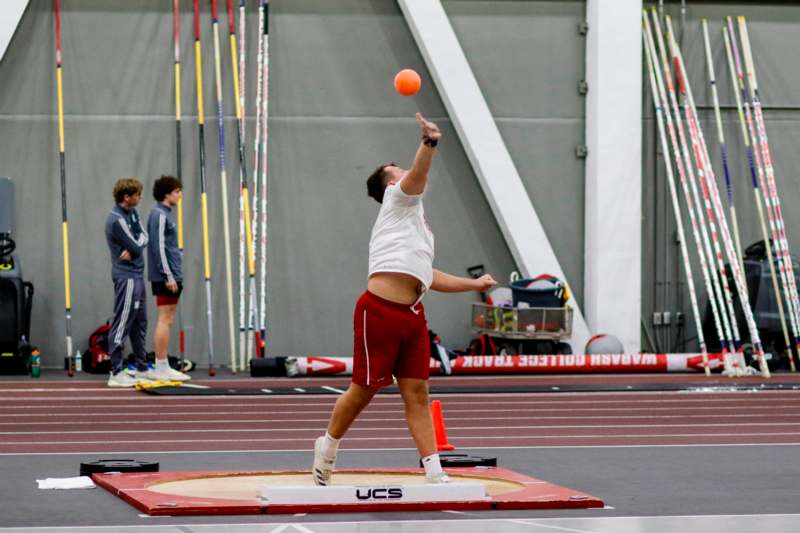 a man in a white shirt and red shorts throwing a ball