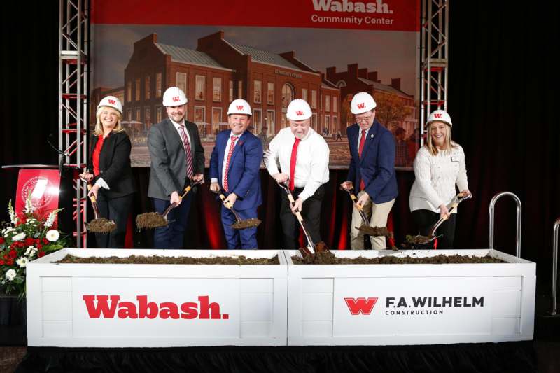 a group of people wearing hard hats shoveling dirt