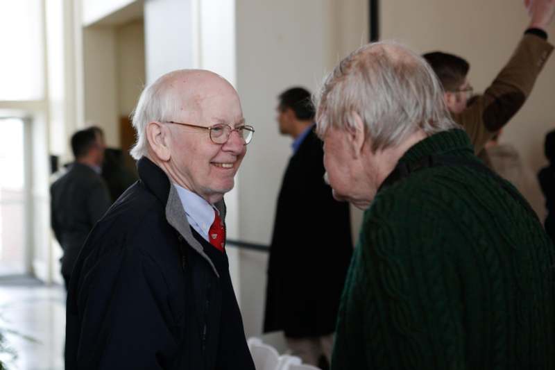 a man in a red tie and glasses talking to another man