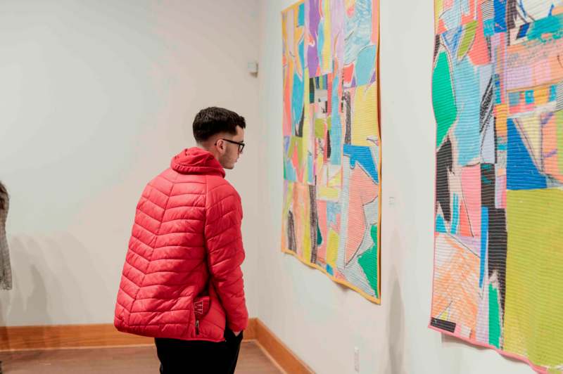 a man looking at a piece of art on a wall