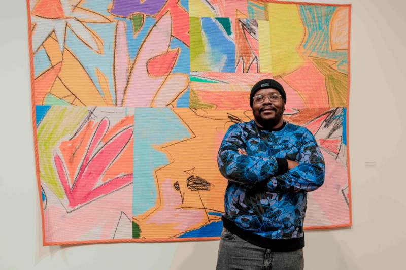 a man standing in front of a colorful artwork