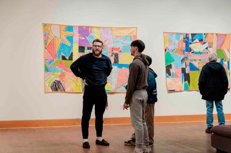 a group of people standing in front of a wall with colorful art on it