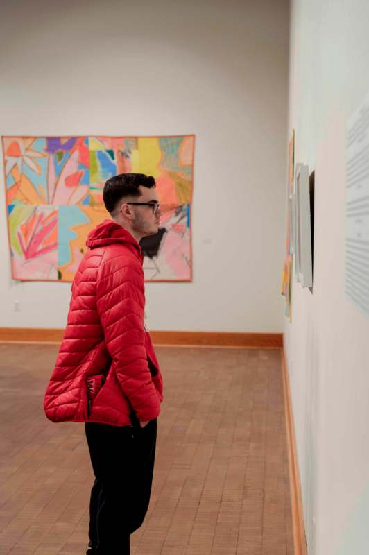 a man in a red coat looking at a piece of art