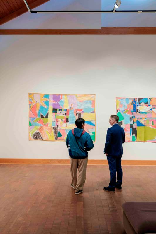 two men looking at a piece of art on a wall