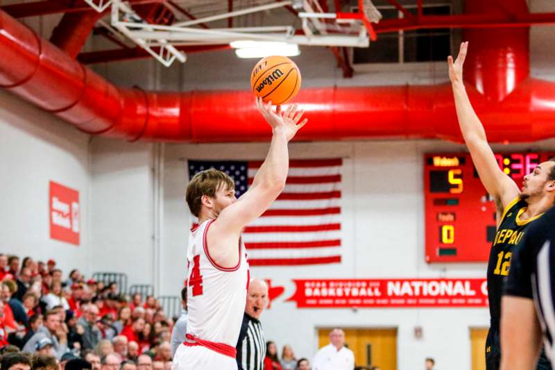 a basketball player in a white uniform with a red ball in the air