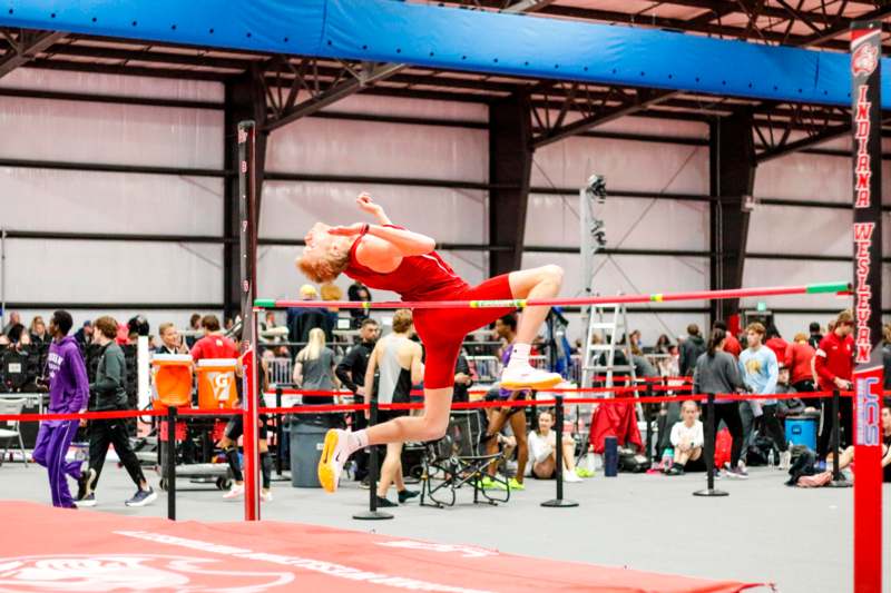 a man jumping over a pole in a gym