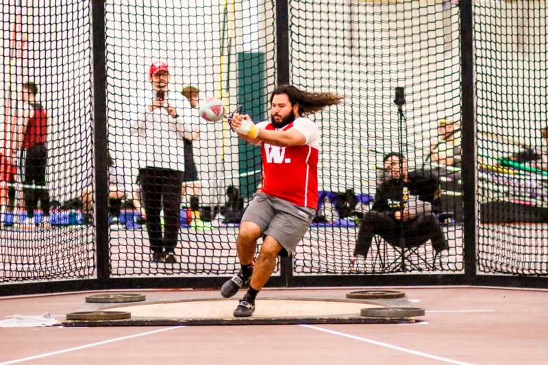 a man in a red shirt hitting a ball with a net