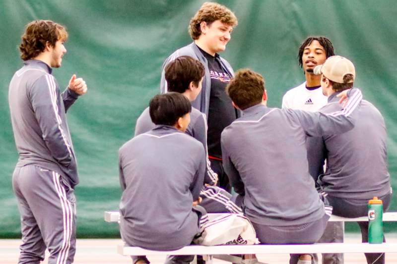 a group of men sitting on a bench talking to each other