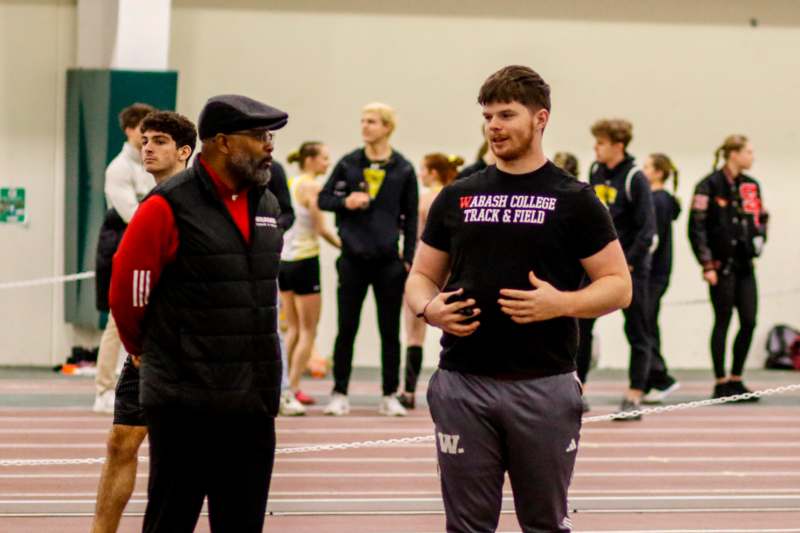 a man standing next to a man on a track