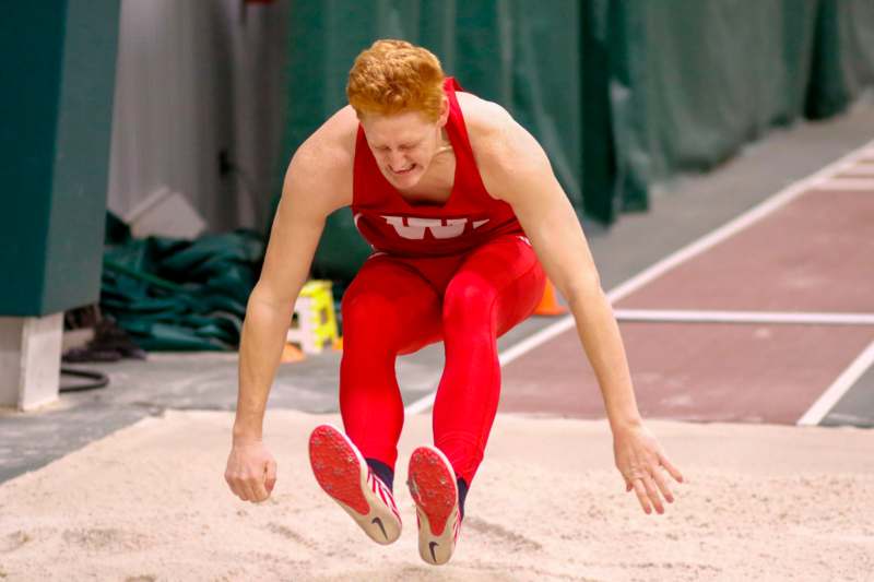 a man in a red uniform jumping over sand