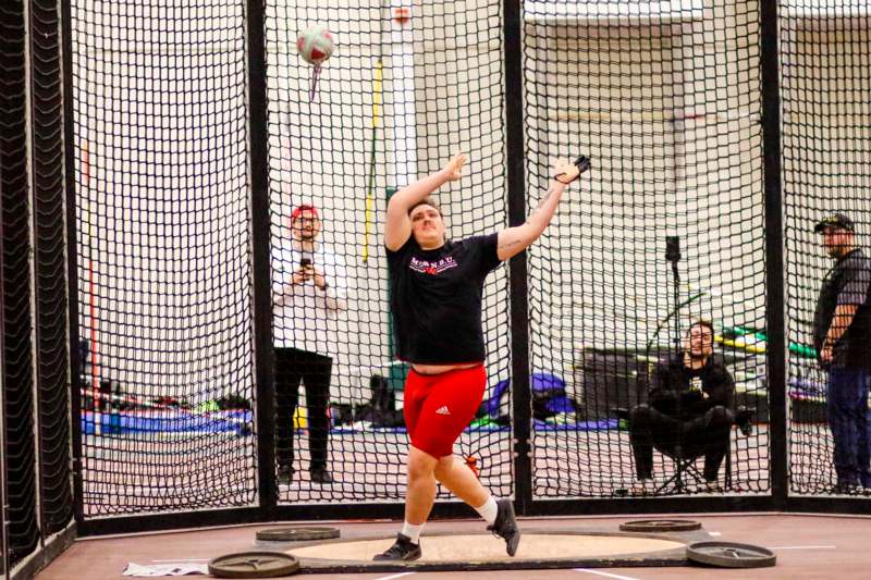 a man in a black shirt and red shorts throwing a ball