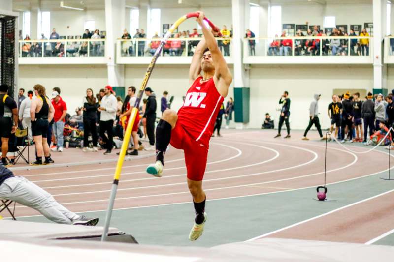 a man jumping in the air with a pole in front of a crowd