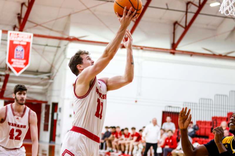 a man in a basketball uniform jumping to shoot a basketball