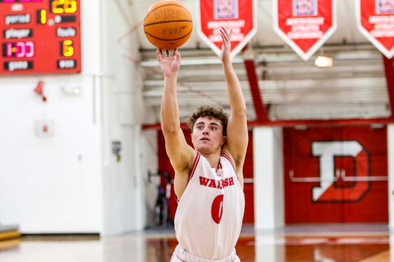 a man in a basketball uniform jumping to shoot a basketball