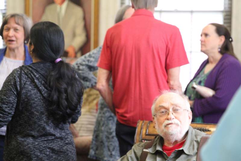 a man sitting in a chair with a group of people in the background