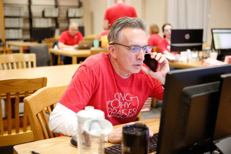 a man in a red shirt talking on a cell phone
