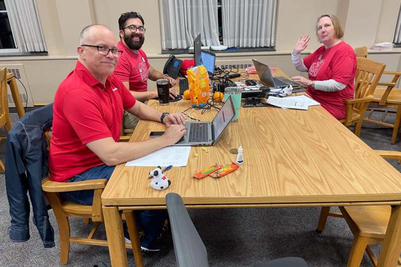 a group of people sitting at a table with laptops