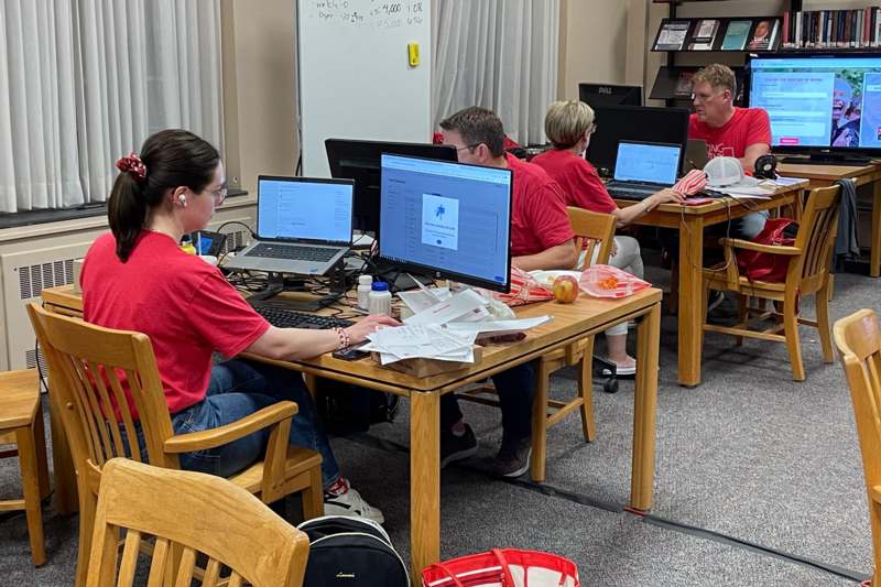 a group of people sitting at a table with computers