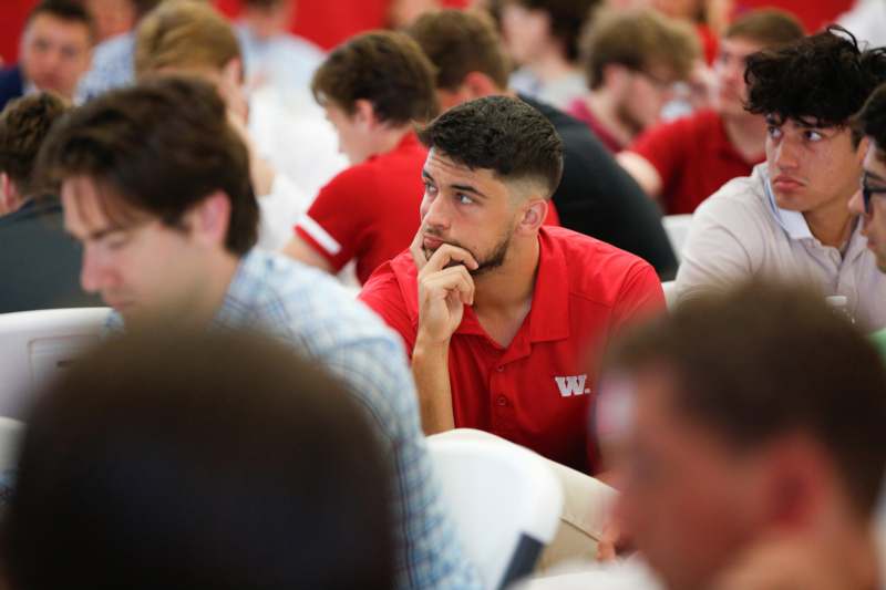 a man in a red shirt sitting in a room with other people