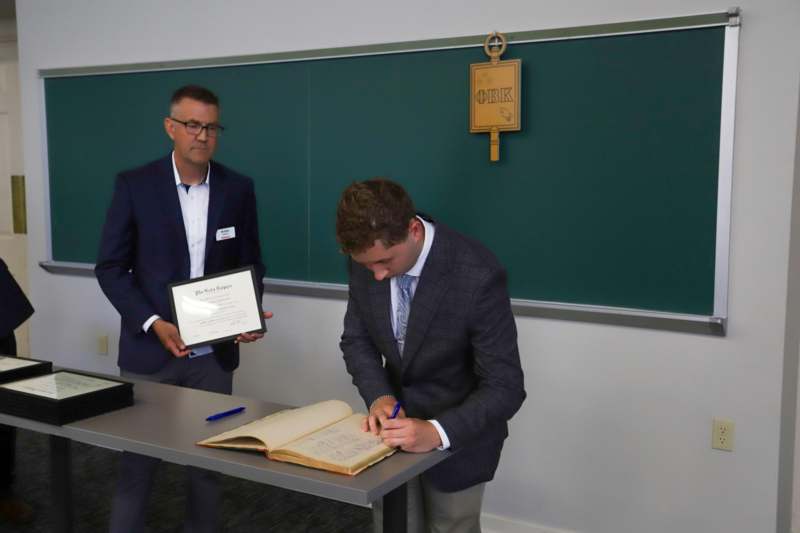 Richard Ballentine signs his name in the Phi Beta Kappa book
