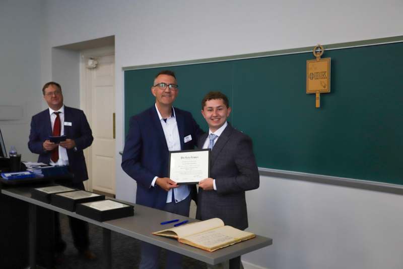 a man holding a certificate and smiling