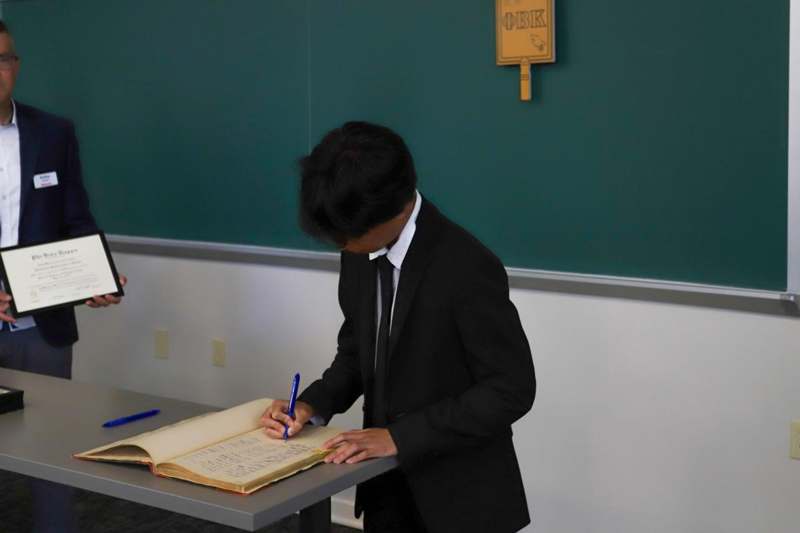 Benjamin Casica-Patton signs the Phi Beta Kappa book.