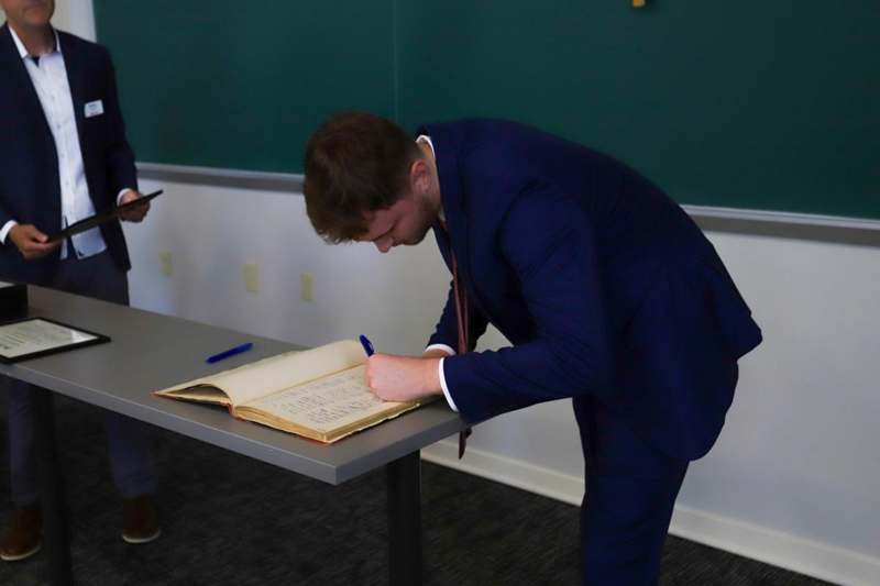 Aidan Geleott signs the Phi Beta Kappa book.