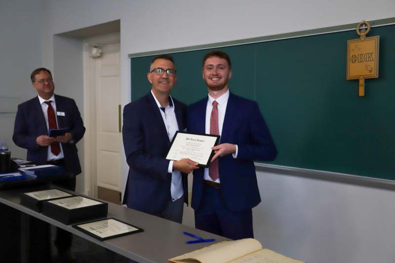 two men in suits holding a certificate
