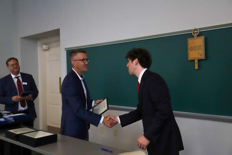 two men shaking hands in a classroom