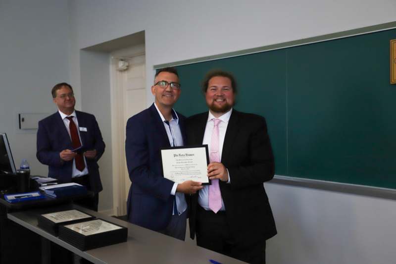 a group of men in suits holding a certificate