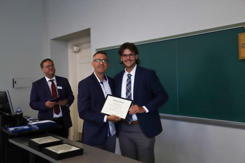 a group of men in suits holding a certificate