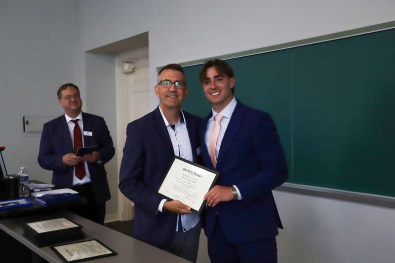a group of men in suits holding a certificate