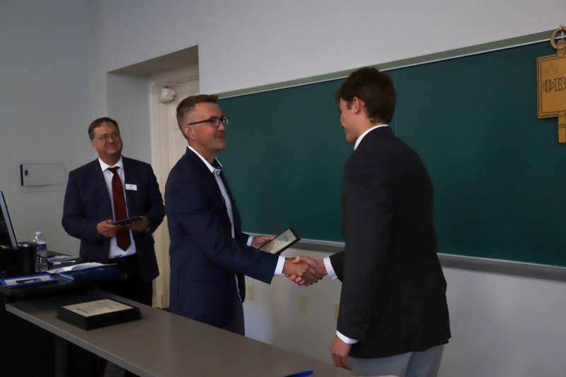 a group of men shaking hands in a classroom