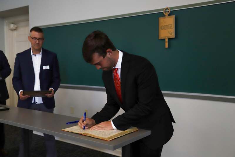 Braden Potters signs the Phi Beta Kappa book.