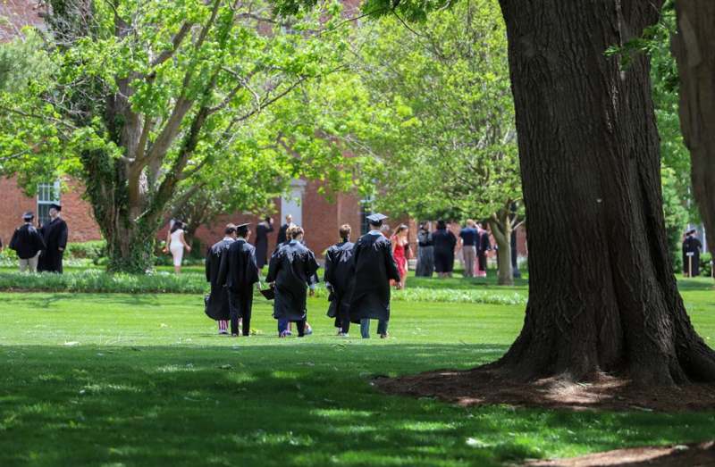a group of people in graduation gowns walking on grass