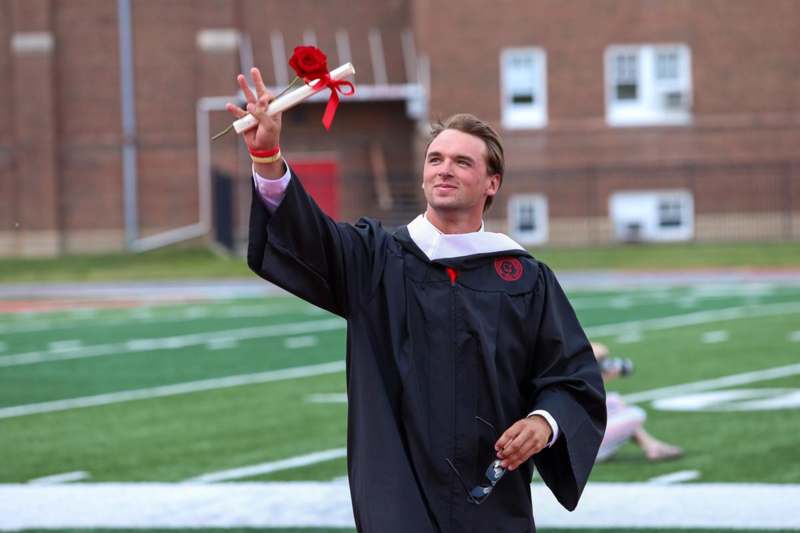 a man in a graduation gown holding a rose