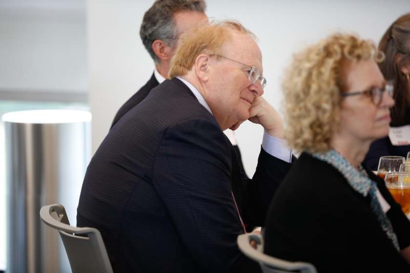 a man in a suit sitting in a room with other people