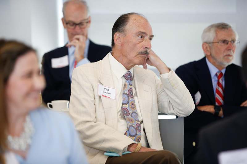 a man in a white suit with his hand on his chin