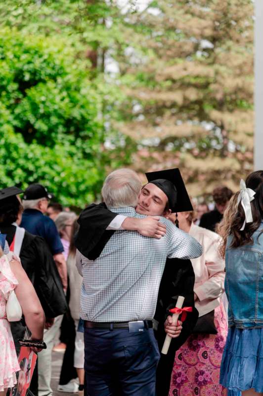 a man hugging a man in a graduation cap